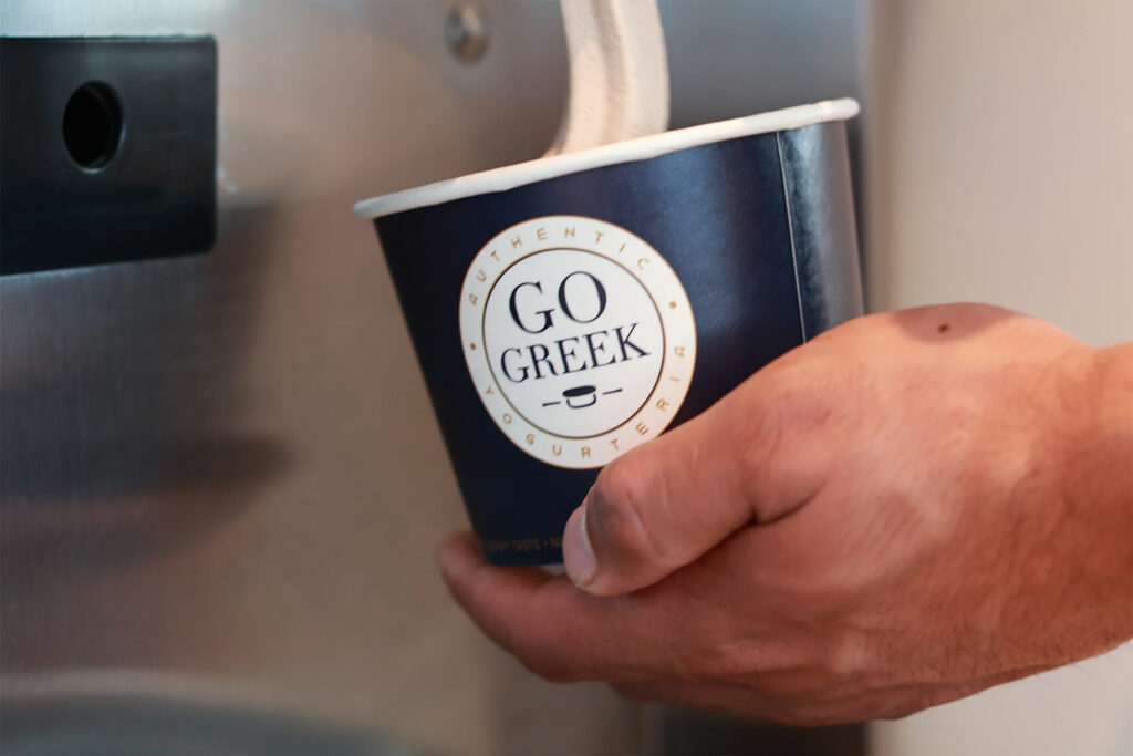 Frozen yogurt being dispensed into a Go Greek Yogurt cup