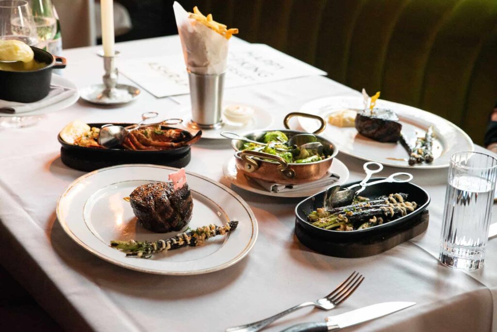 Assorted entrées and truffle fries on a table at Maple & Ash