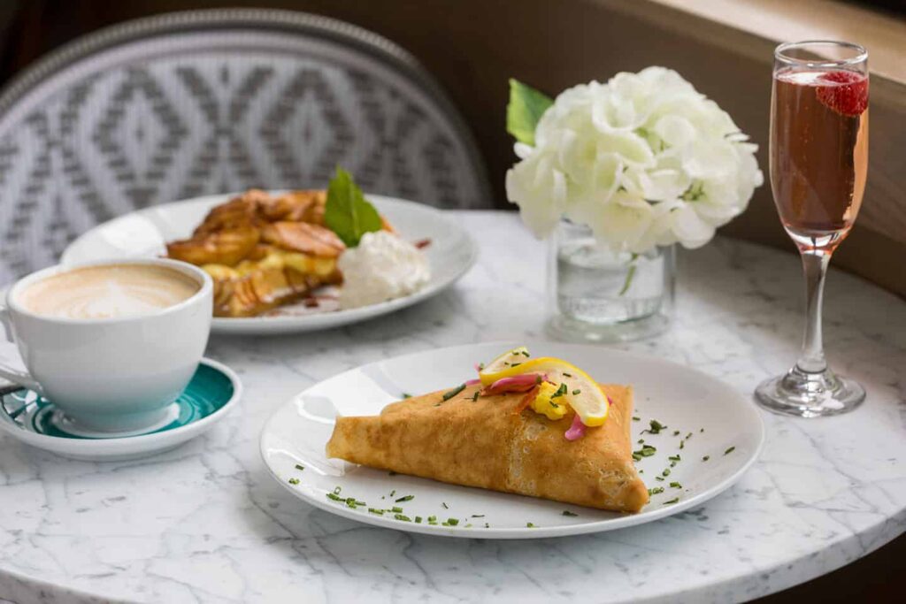 Crepes on a table with wine and a latte at Sweet Paris Crêperie and Café